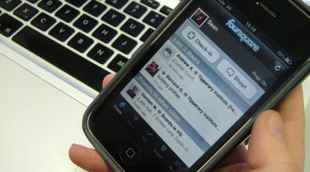 Image of a hand holding a phone with foursquare app screen